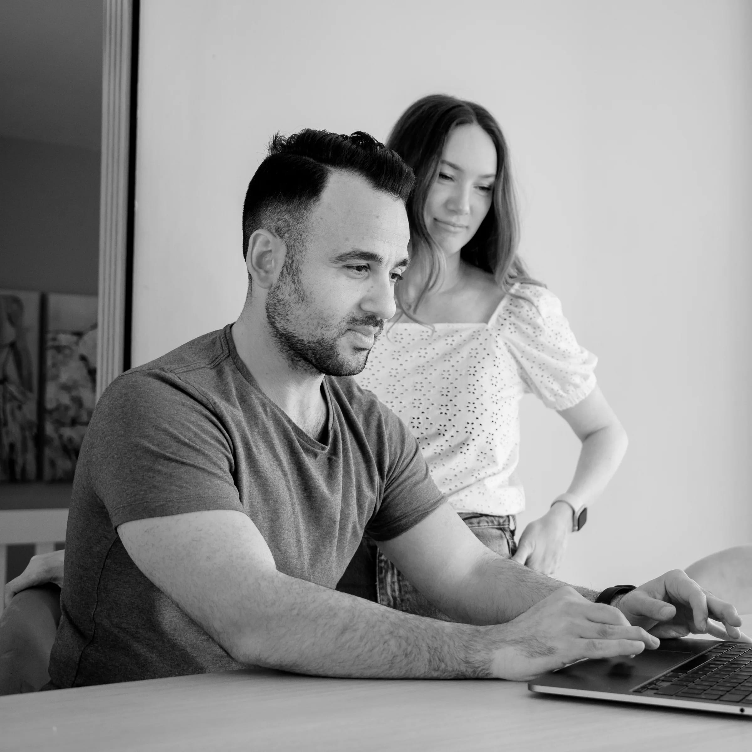 Nader och Bella på NoBella arbetar tillsammans vid en laptop, svartvitt foto